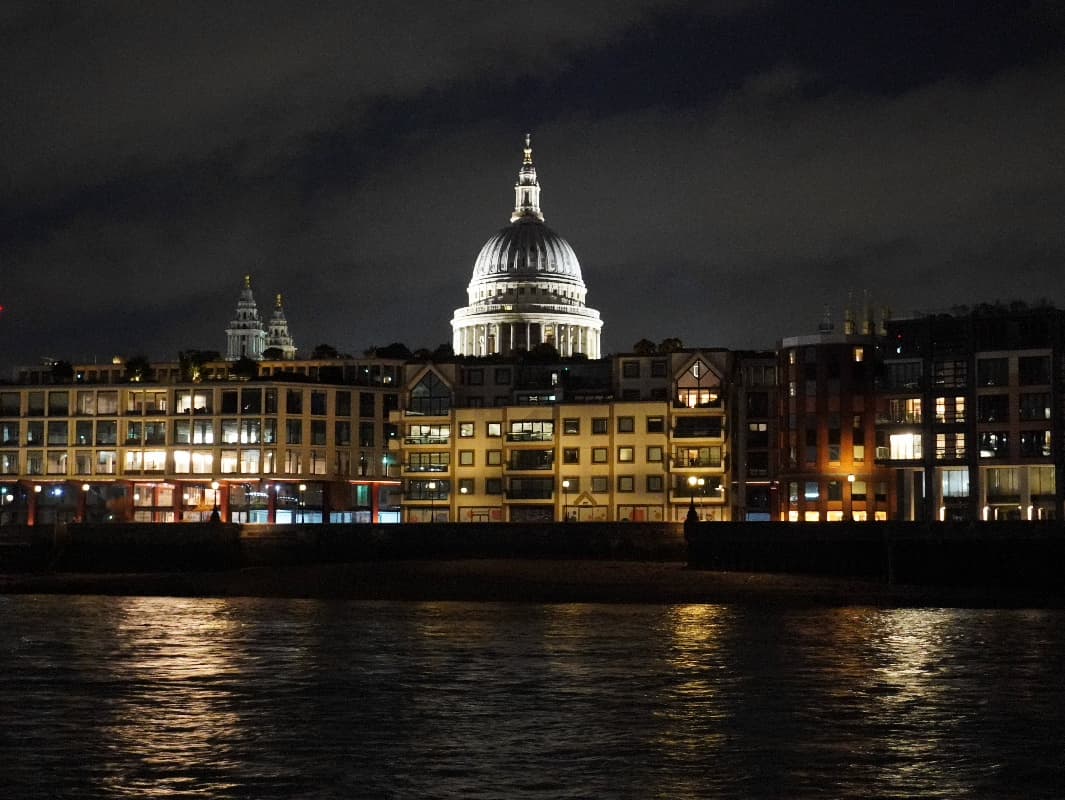 St Paul's Cathedral floodlit at night, seen across the Thames above a row of riverside buildings